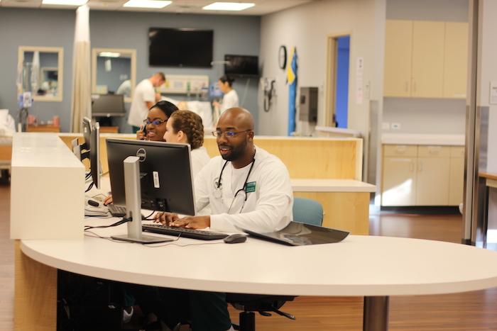 A nursing professional reviewing data at a computer.