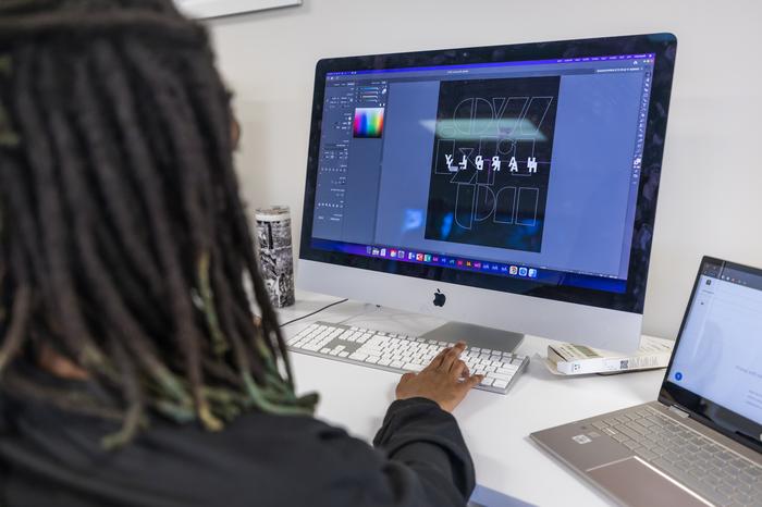 Graphic design student utilizing Adobe graphic design programs on a computer